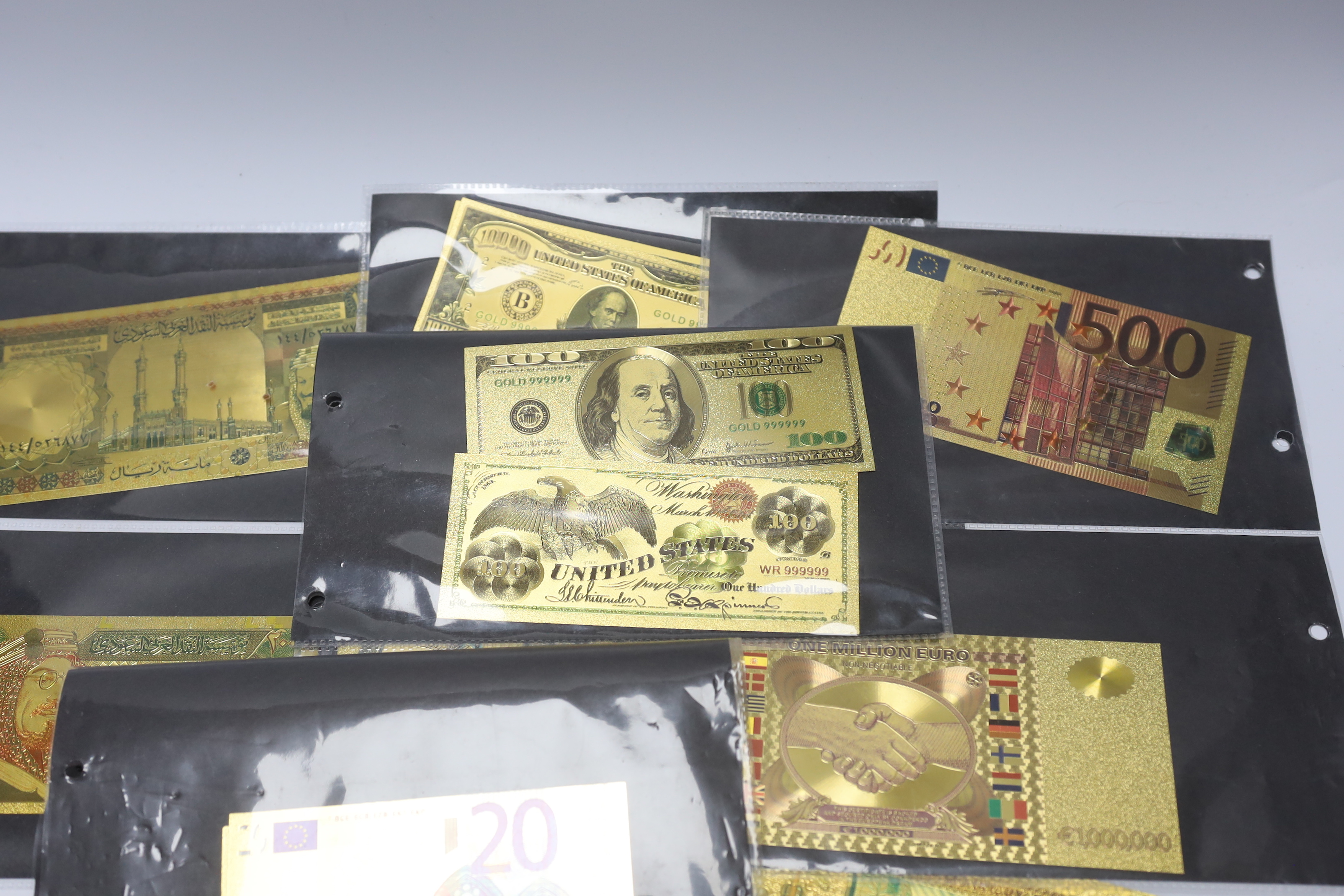 A collection of gold plated medallions and bank notes